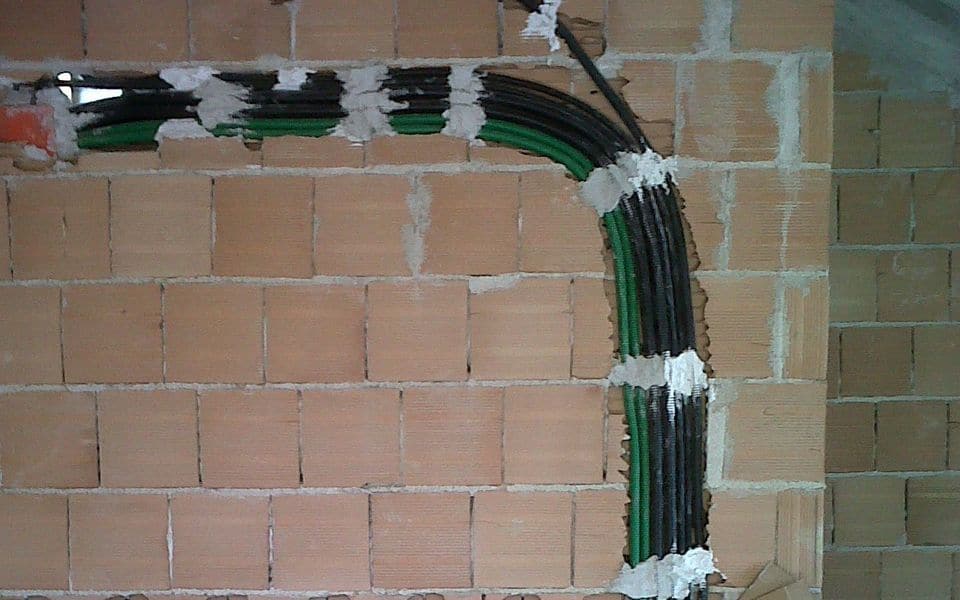 Canalizaciones y cables sobre un muro de ladrillo en un edificio en construcción