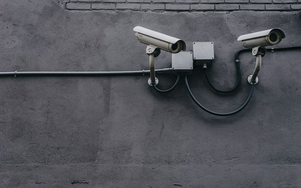 Two bullet surveillance cameras mounted on a building wall for optical coverage