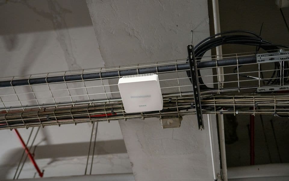 Un punto de acceso Wi-Fi empresarial montado en una bandeja de cables de techo
